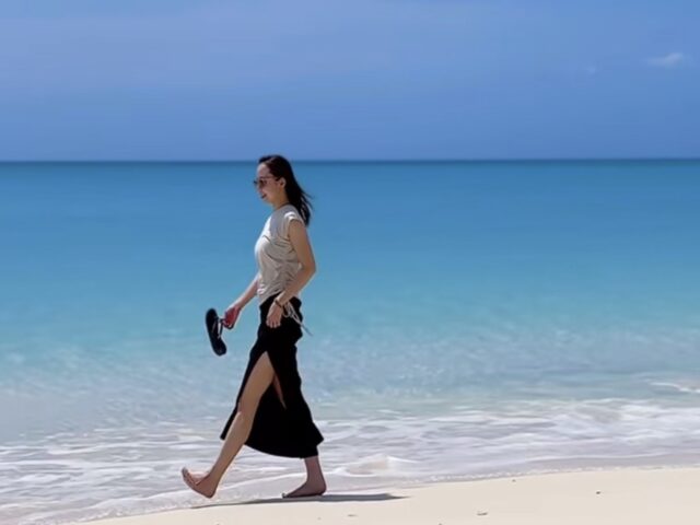 오키나와 외딴 섬의 맑고 푸른 바다와 하얀 모래사장을 맨발로 걷고 있는 여성