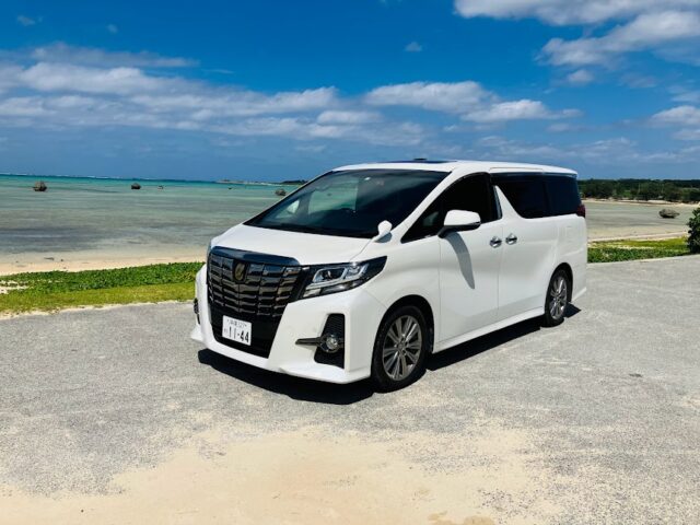 石垣島の海を背景にした白いアルファードレンタカー