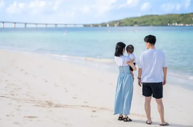 커다란 다리를 배경으로 오키나와 외딴 섬의 하얀 모래사장에 서 있는 가족