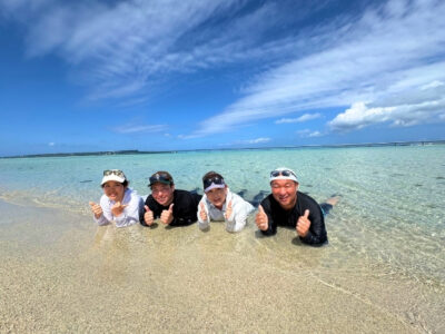 宮古島「ユニの浜」への上陸体験。干潮時に現れる白い砂洲を散策する女性たちと、背景に広がる宮古ブルーの海