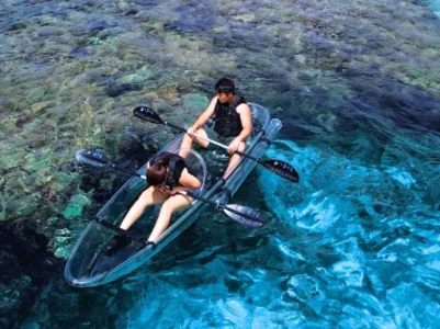 宮古島の透明な海の上で、海底を覗き込みながらクリアカヤックを漕ぐ男女