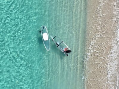 ユニの浜のドローン撮影。宮古島の青いグラデーションの海に、一筋の白い砂洲とクリアSUPが浮かぶ絶景