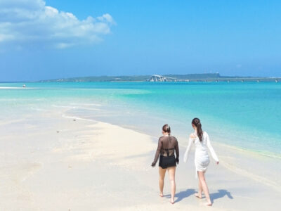 宮古島「ユニの浜」への上陸体験。干潮時に現れる白い砂洲を散策する女性たちと、背景に広がる宮古ブルーの海