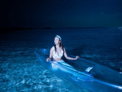 星空が広がる夜の海に浮かぶマーメイド姿の女性