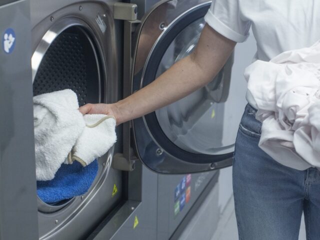 洗濯中の服を取り出すシンプルなコインランドリー