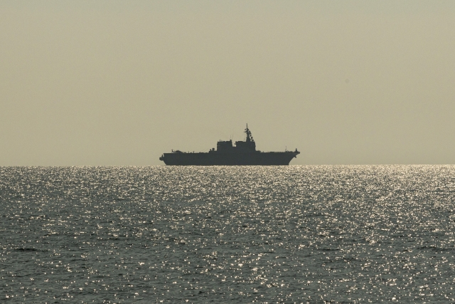 夕焼けの海原を航行する護衛艦のシルエット